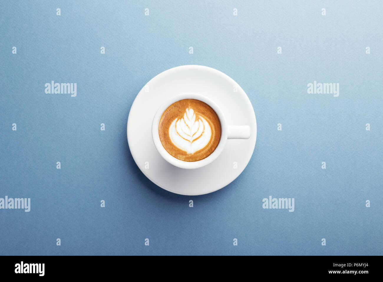 Eine Tasse Cappuccino mit schönen Latte Art auf blauem Hintergrund. Ansicht von oben, zentrale Komposition. Stockfoto Eine Tasse Cappuccino mit schönen Latte Art auf blauem Hintergrund. Ansicht von oben, zentrale Komposition. Stockfoto