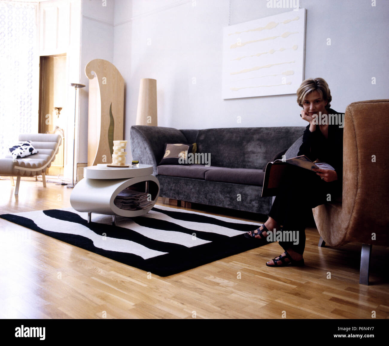 Porträt einer Frau, die in einer frühen noughties urbanen Wohnzimmer sitzen Stockfoto