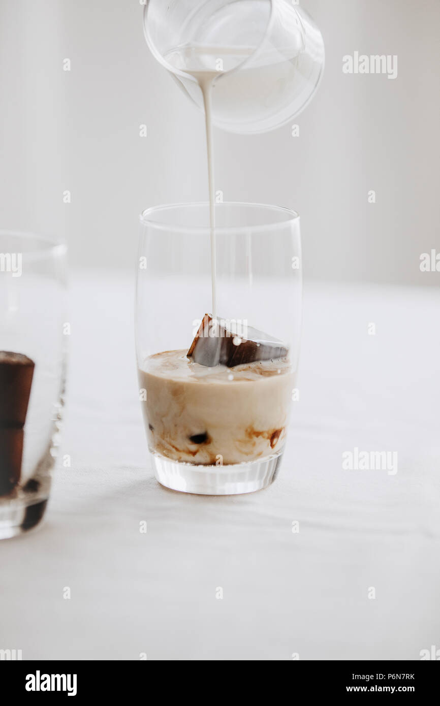 Gefrorenen Kaffee Eiswürfel in ein Glas mit Milch goß einen erfrischenden  Sommer Eiskaffee trinken zu machen. Weißer Hintergrund Stockfotografie -  Alamy