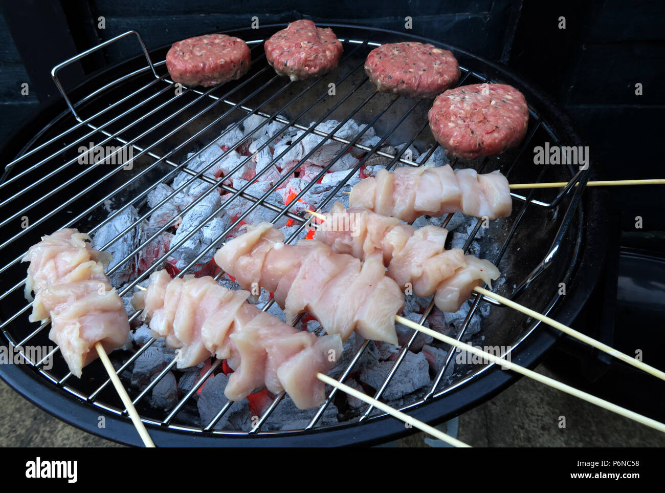 Rohes Huhn, auf einem Grill, rohes Huhn, ungekochte Fleisch, über Holzkohle auf einem Garten Grill, Sommer BBQ Stockfoto