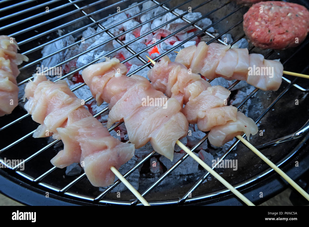 Rohes Huhn, auf einem Grill, rohes Huhn, ungekochte Fleisch, über Holzkohle auf einem Garten Grill, Sommer BBQ Stockfoto