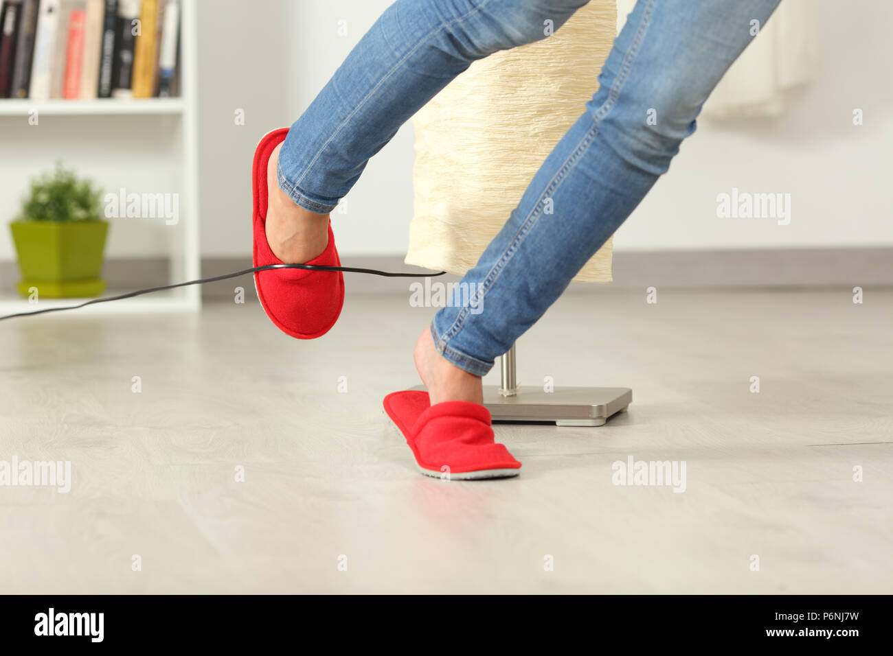 Nahaufnahme einer Frau die Beine mit einem elektrischen Kabel zu Hause stolpern Stockfoto