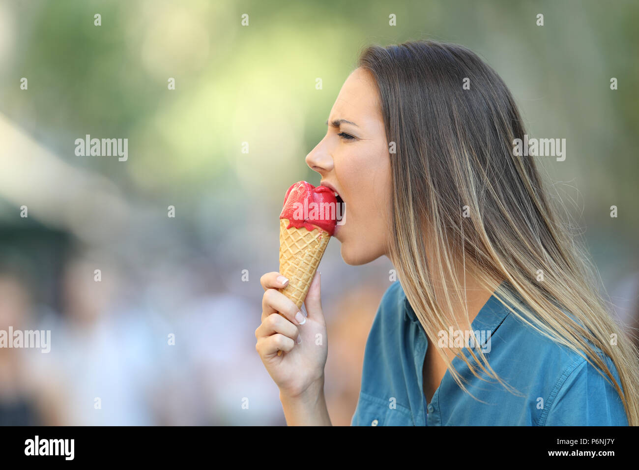 Seitenansicht Porträt einer Frau, die mit einer Überempfindlichkeitsreaktion beißen ein Eis Stockfoto