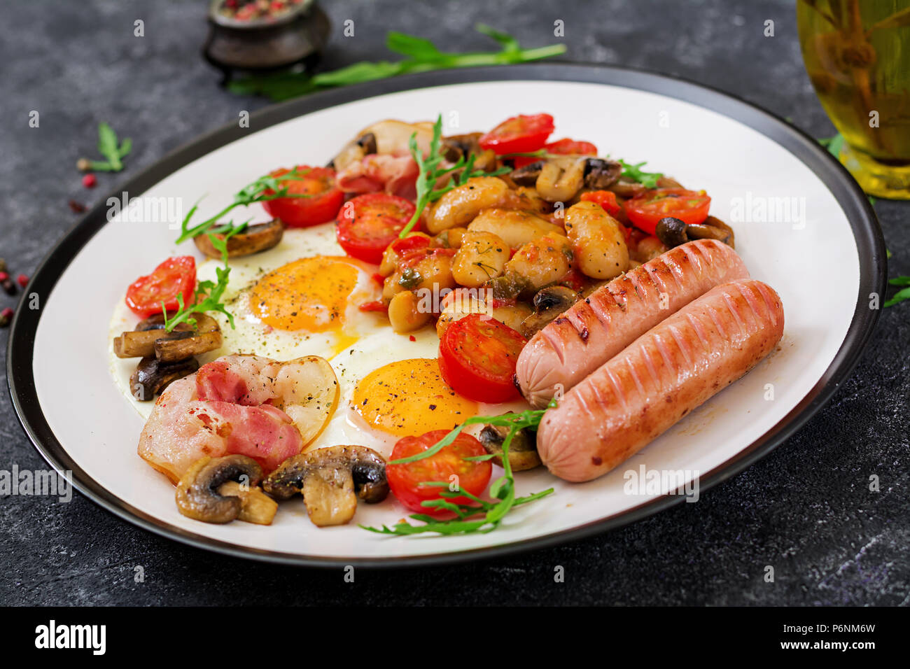 Englisches Frühstück - Spiegeleier, Bohnen, Tomaten, Champignons, Speck und Würstchen. Leckeres Essen. Stockfoto