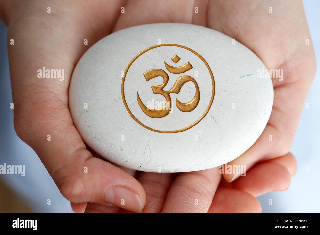 Die Om oder Aum Symbol von Hinduismus und Buddhismus auf einen weissen Stein. Stockfoto
