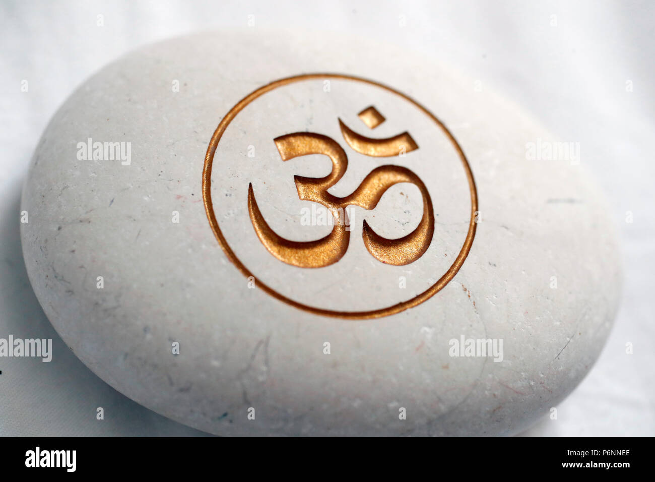 Die Om oder Aum Symbol von Hinduismus und Buddhismus auf einen weissen Stein. Stockfoto