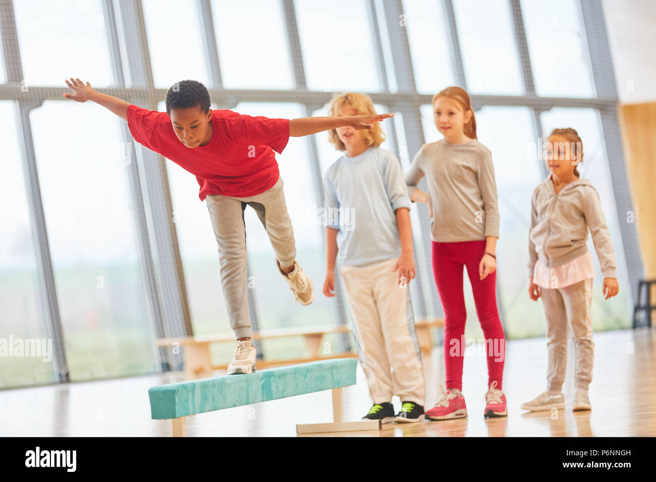 Kinder machen Schule Sport und Balance auf einem Schwebebalken Stockfoto