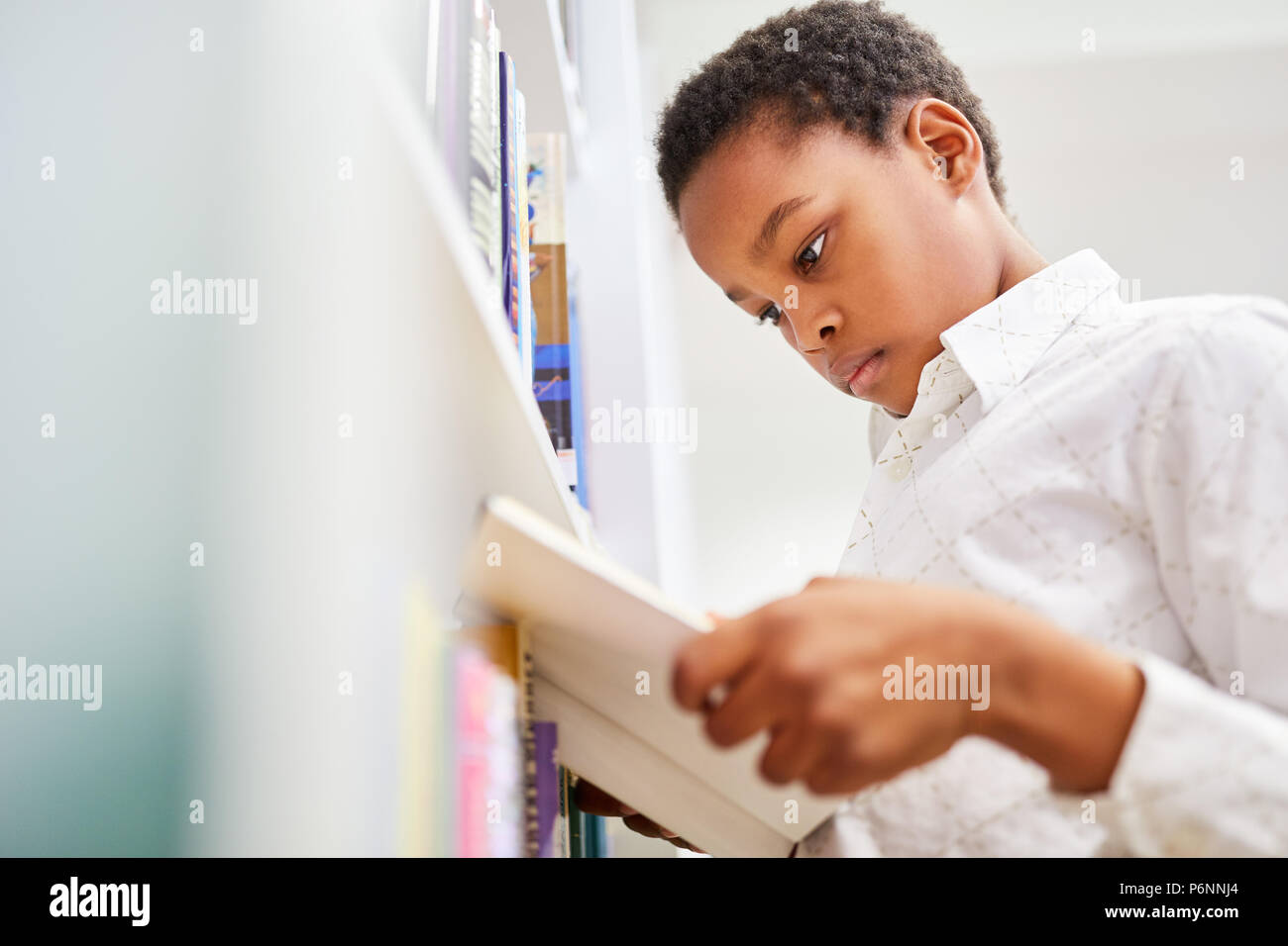 Afrikanische Schüler in der Bibliothek der Schule ist es ein Buch konzentriert lesen Stockfoto