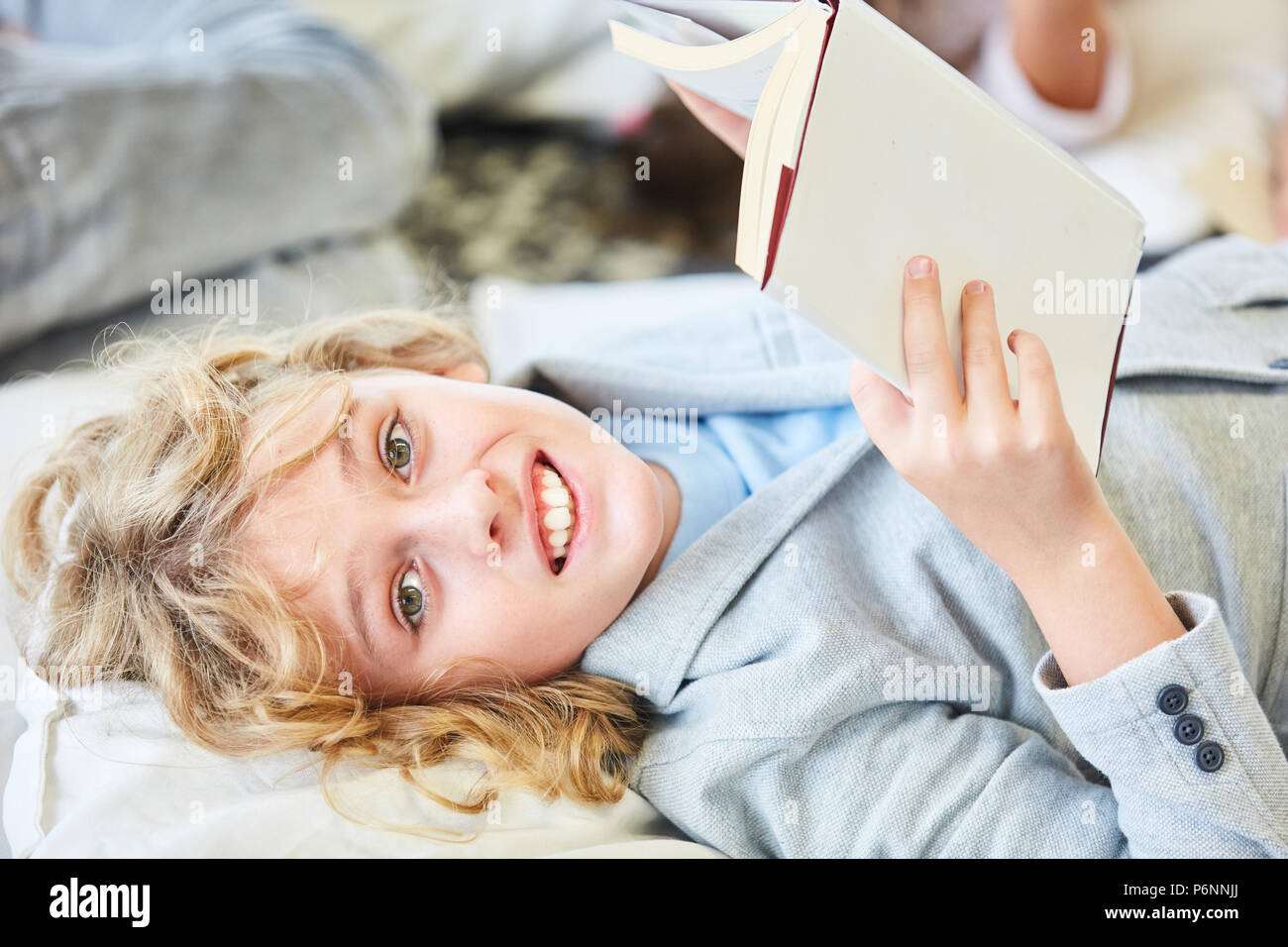 Blonde Junge liest Buch ein spannendes Kinderprogramm oder Sachbuch für die Schule Stockfoto