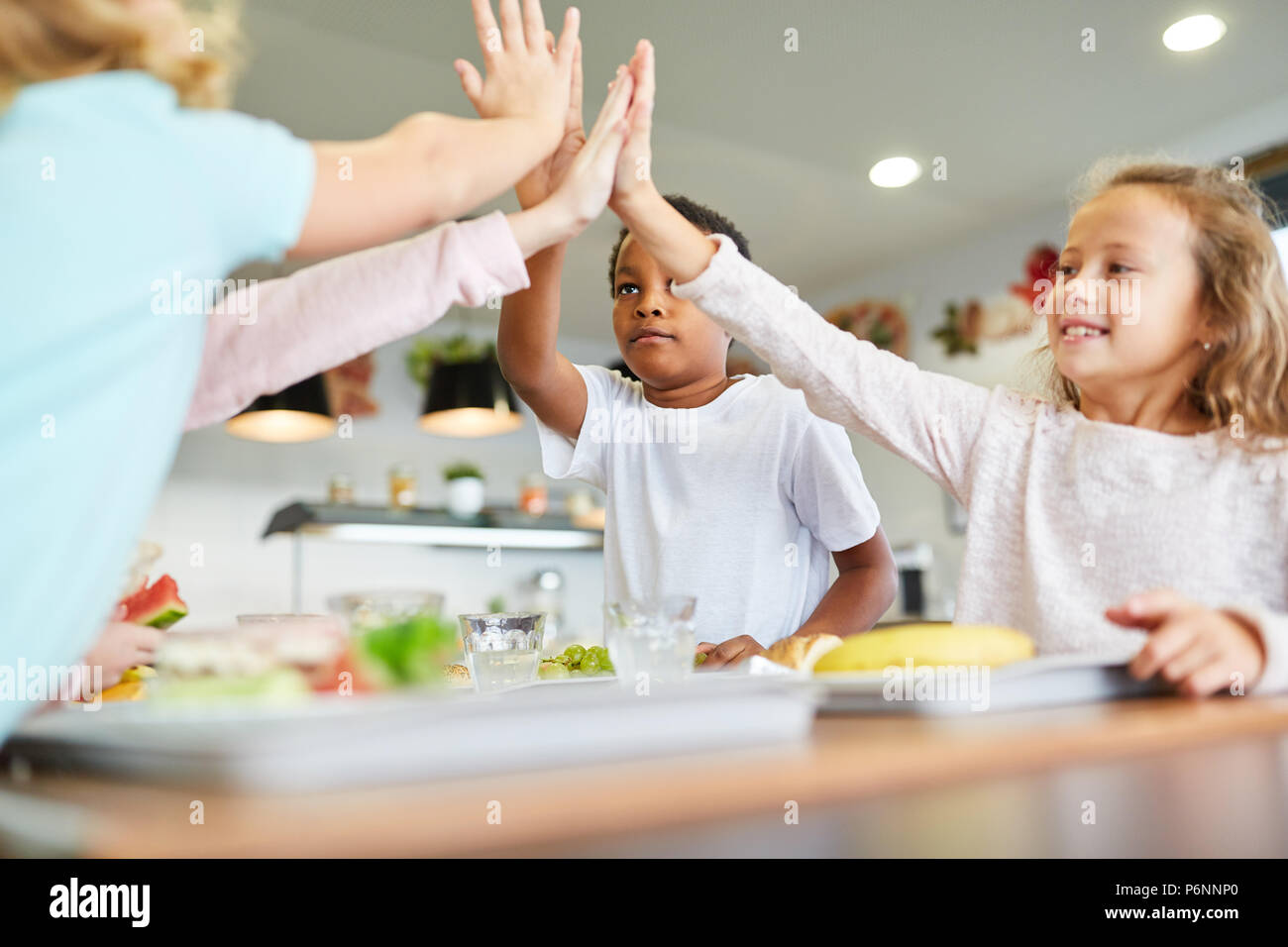 Gruppe von Kindern in der Schule eine Cafeteria geben sich selbst eine hohe fünf Stockfoto