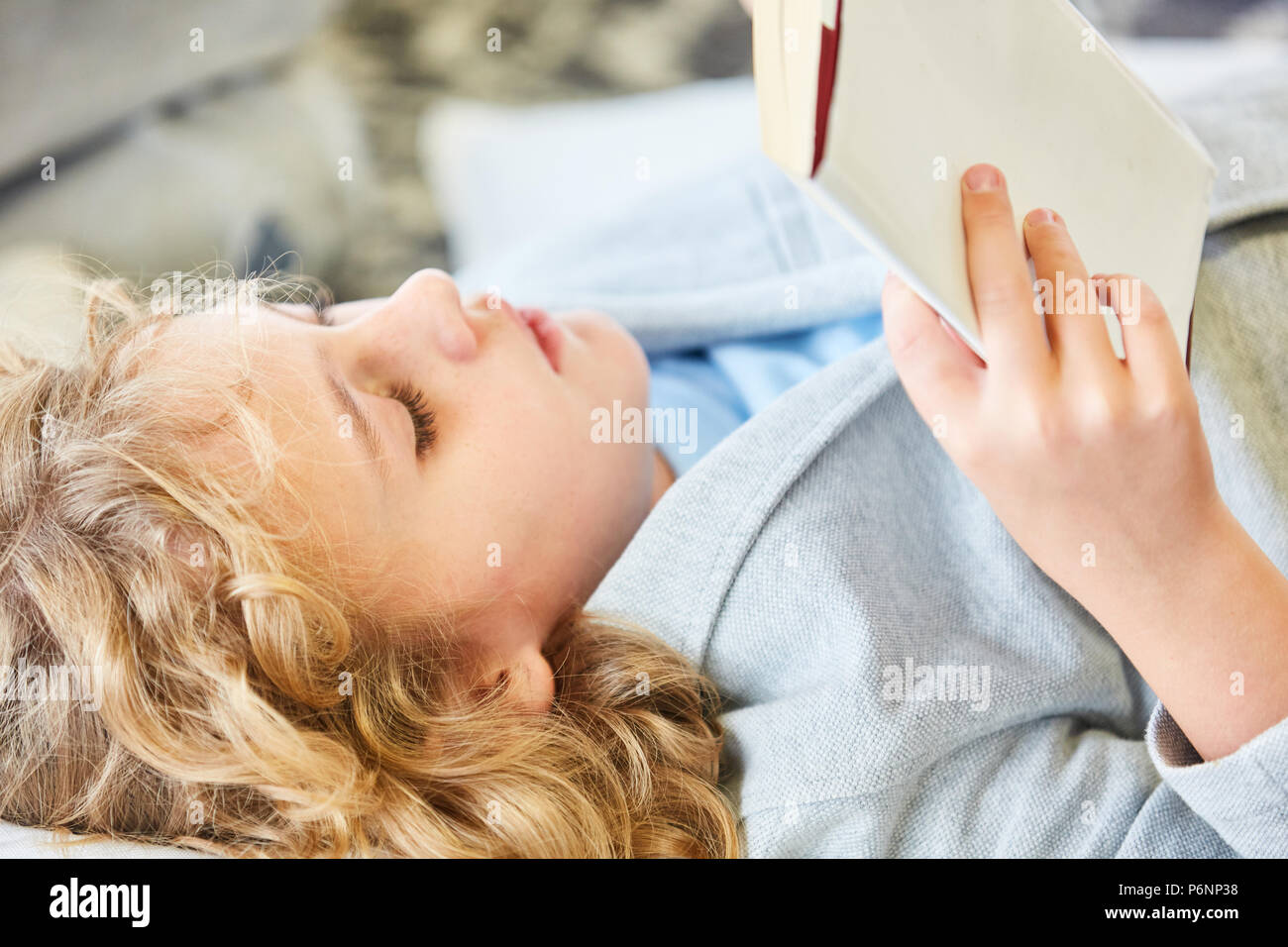 Blonde Junge liest in einem spannenden Storybook oder Sachbuch Stockfoto