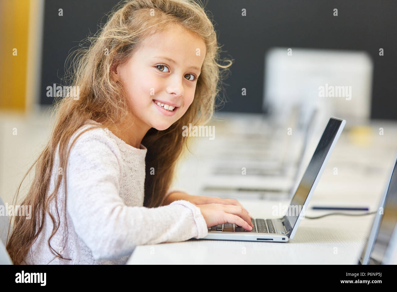 Happy girl im Klassenzimmer einer Grundschule mit Tablet-PC Stockfoto