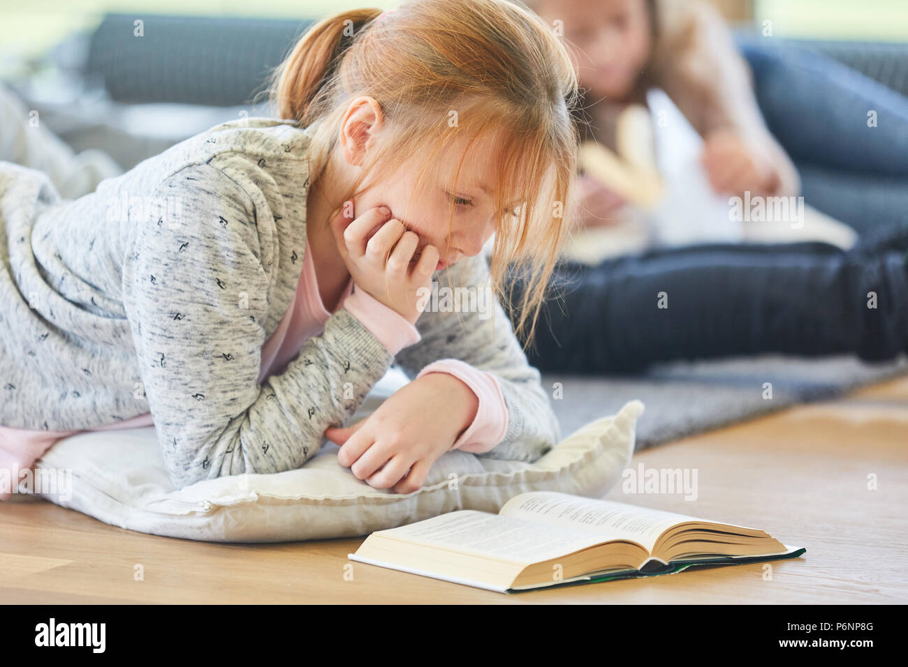Blonde Mädchen liest ein storybook oder Sachbuch konzentriert Stockfoto