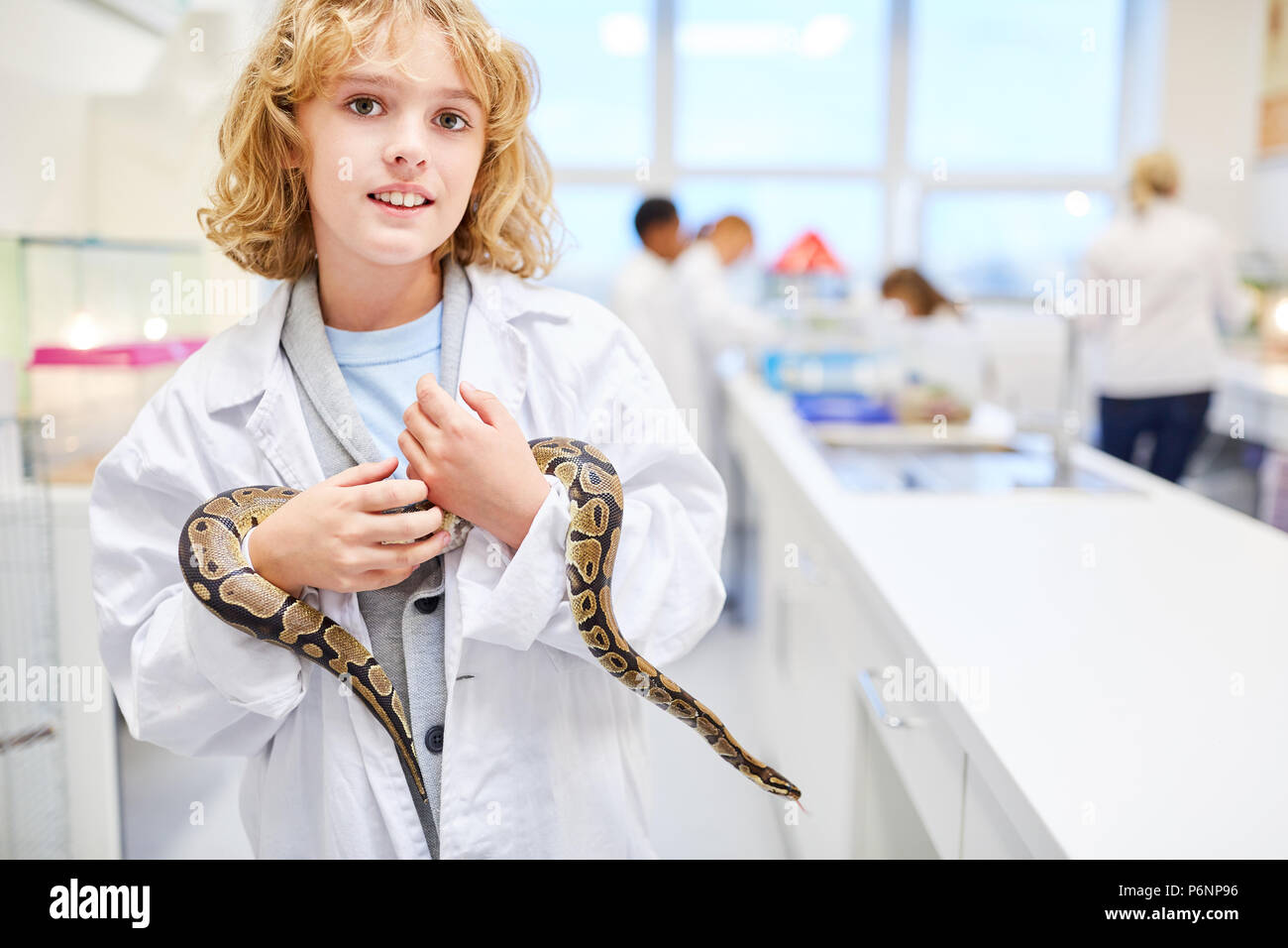 Schüler kümmert sich um eine Schlange in der Grundschule Unterricht Biologie Stockfoto