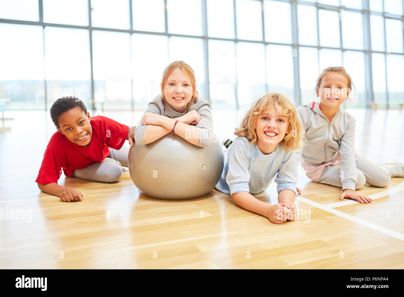 Gruppe von Kindern in der Grundschule Sportunterricht mit einem Gymnastikball Stockfoto
