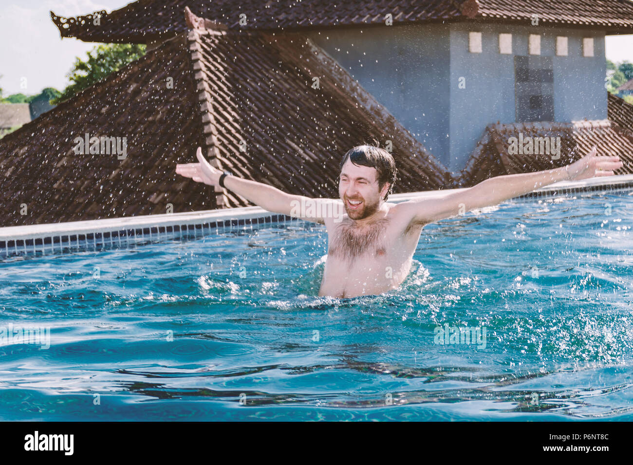 Portrait von Glücklich lächelnde junge Mann mit Händen, die in den Pool auf dem Dach. Emotionen, Freude, Glück, aufgeregt, positiv, vergnügt, froh Stockfoto