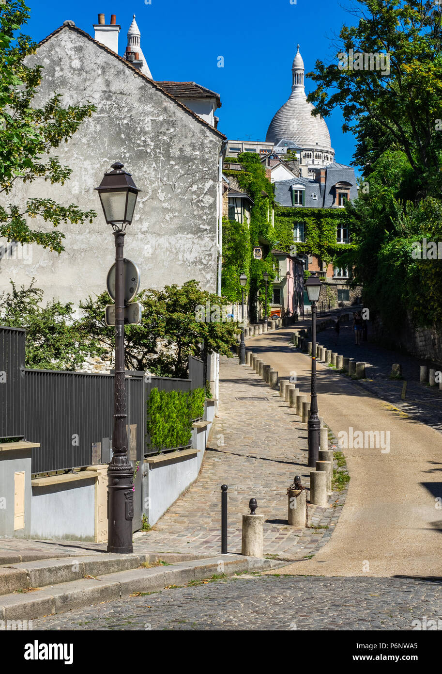Eine kleine Straße in Montmartre Viertel von Paris mit dem Kuppeln der Sacre Coeur im Hintergrund Stockfoto