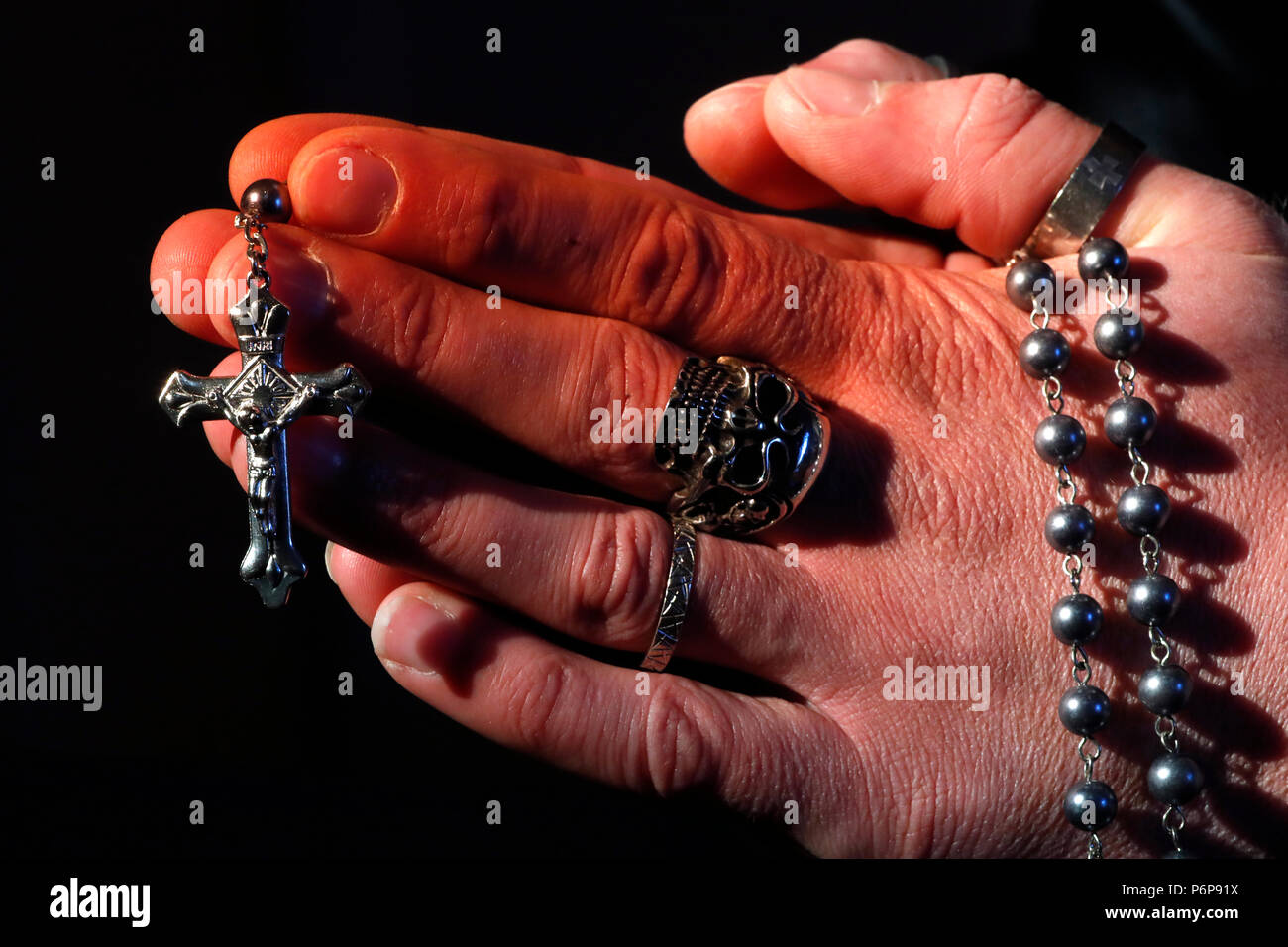 Mann mit Totenkopf Ring beten den Rosenkranz. Close-up. Frankreich. Stockfoto