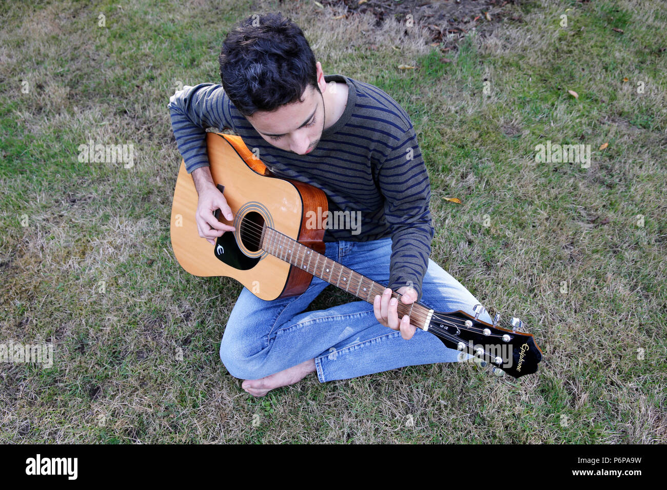 Junge Mann spielt eine Gitarre in einem Garten. Frankreich. Stockfoto