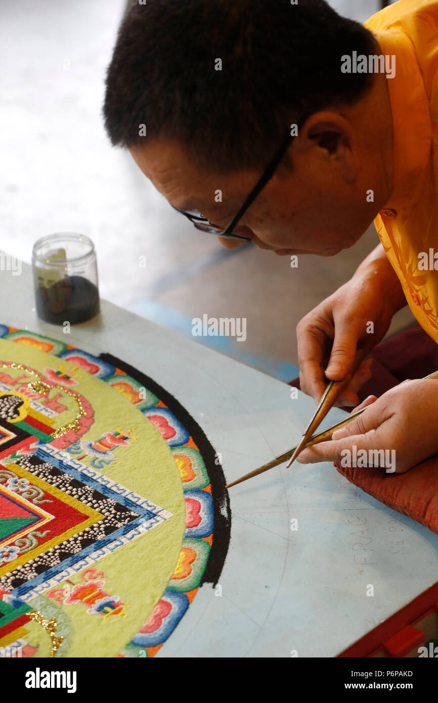 Tibetischen Mönch arbeitet sorgfältig auf einem bunten Sand Mandala. Stockfoto