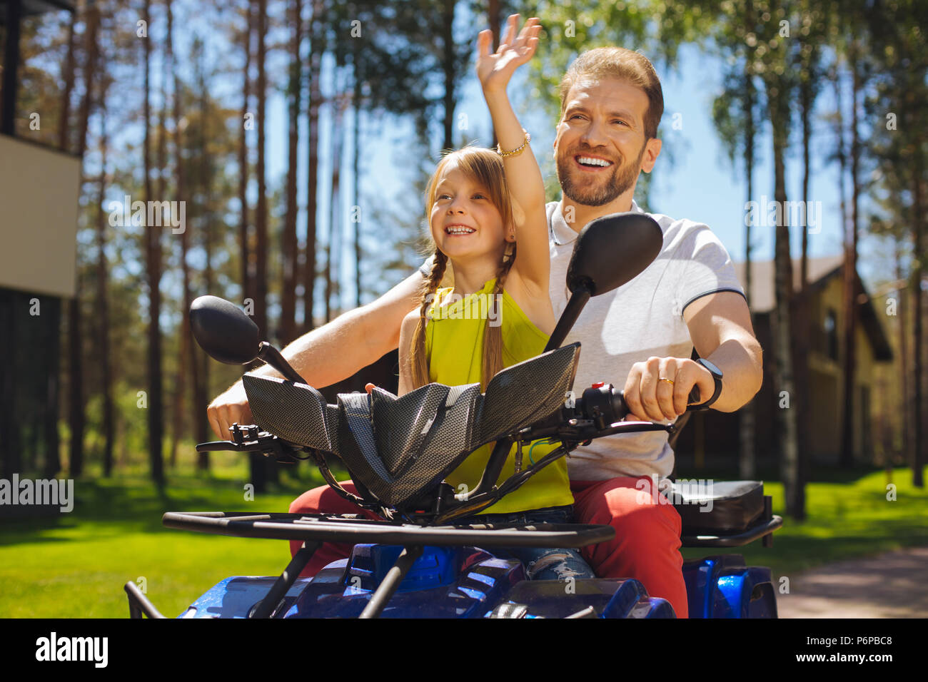 Fröhliches Mädchen fahren ATV mit ihren Daddy Stockfoto