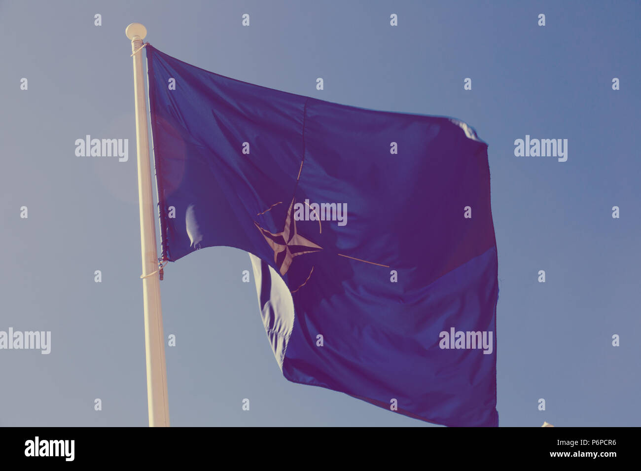 Flagge der NATO über flagstaff Winken gegen den blauen Himmel Stockfoto