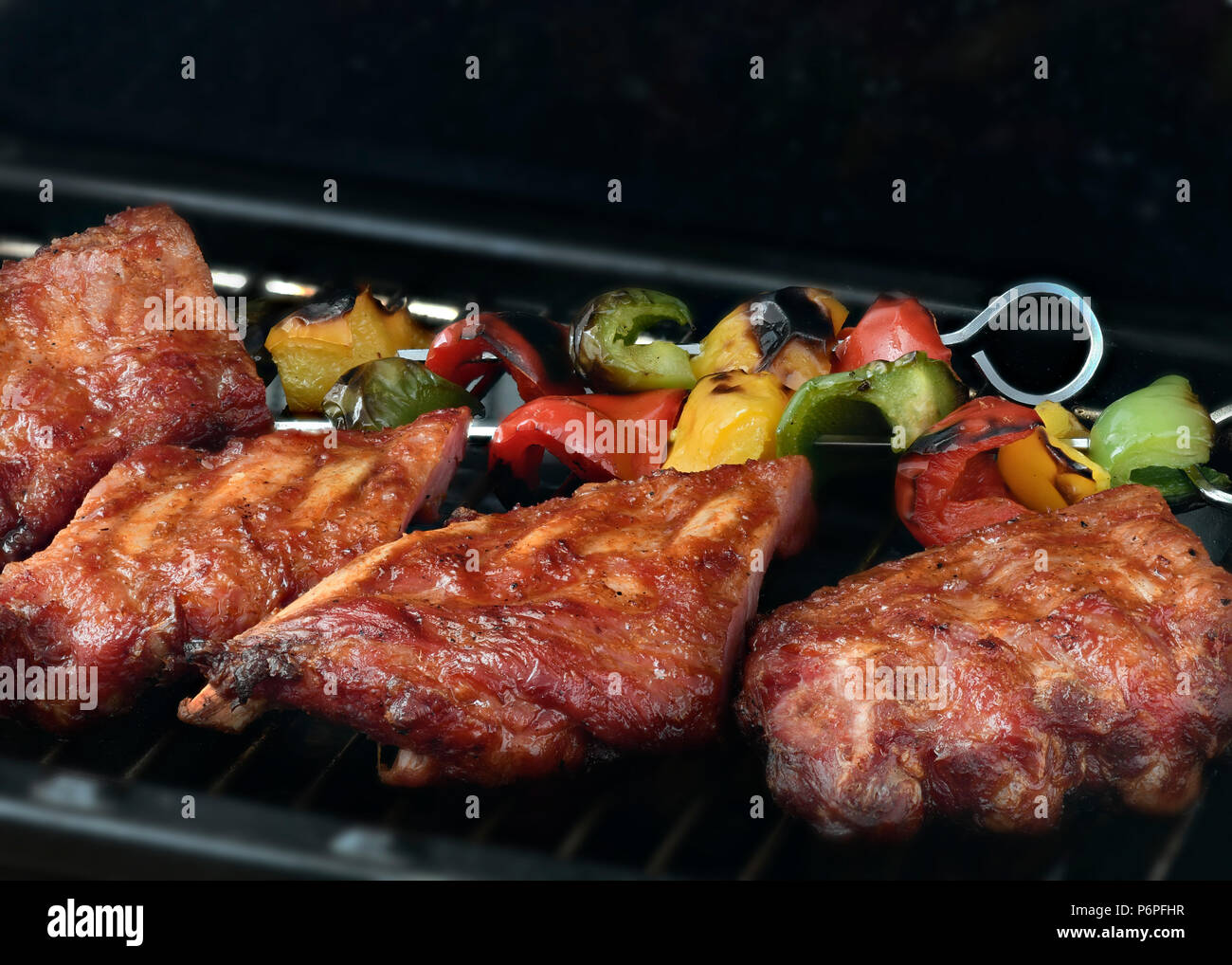 Barbecue Spare Ribs mit grünen und roten Paprika, dunklen Hintergrund für Kopie Raum Stockfoto