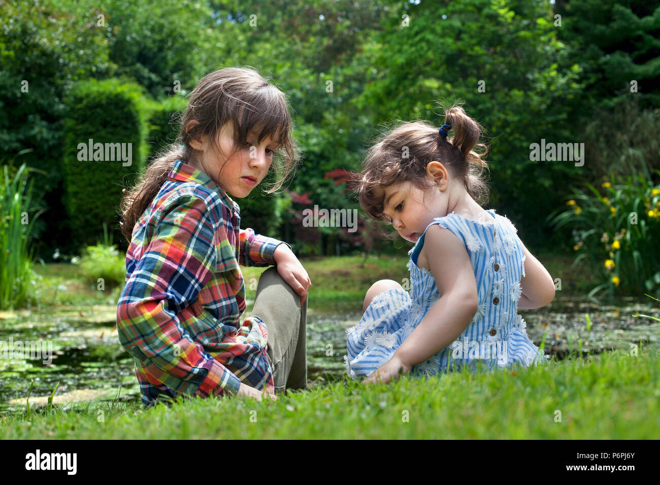 Junge und Mädchen sitzen durch Teich beobachten das Baby Frösche. Stockfoto
