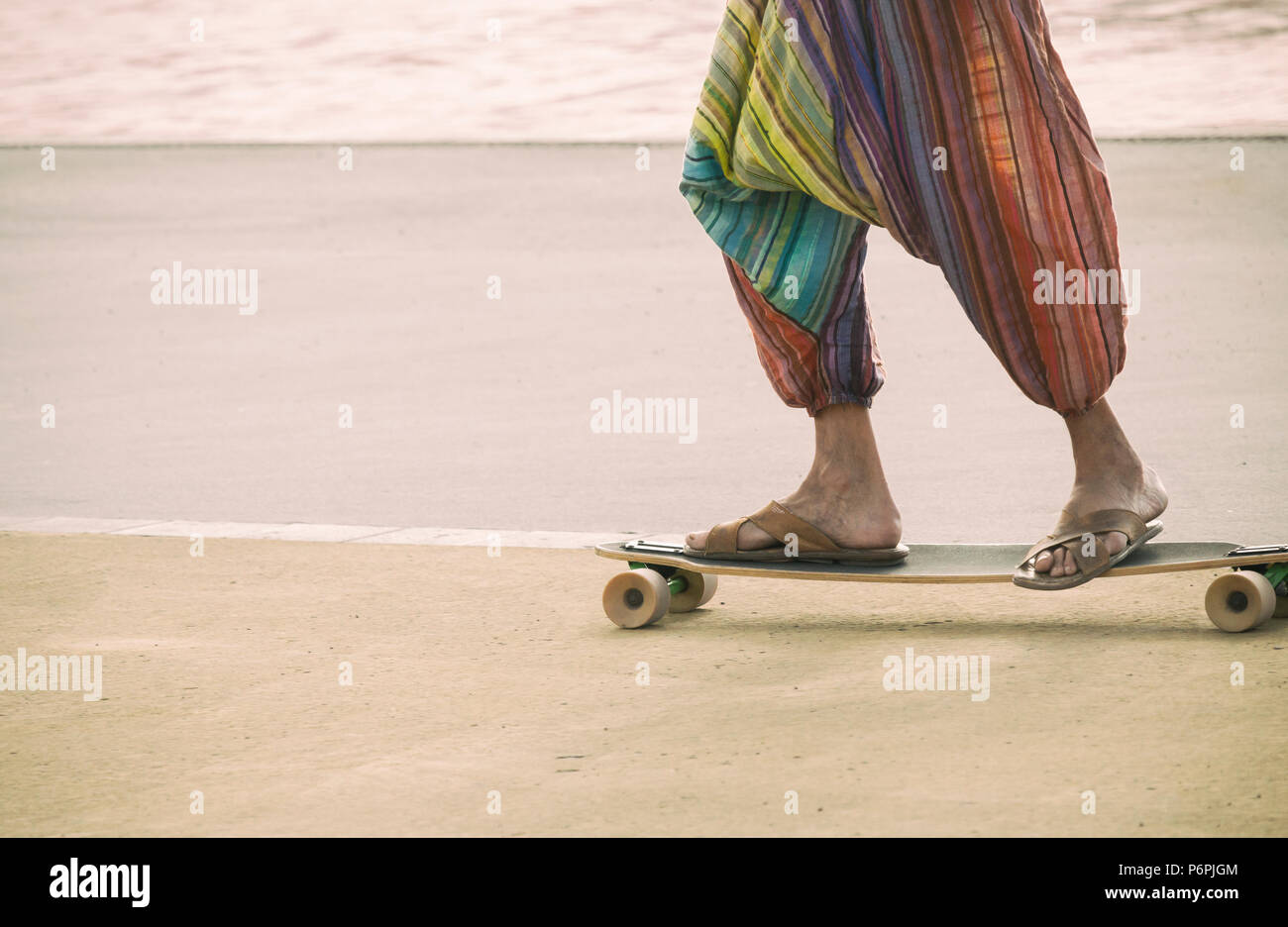 Hippy reiten ein Skateboard tragen Flip Flops/Sandalen. Stockfoto