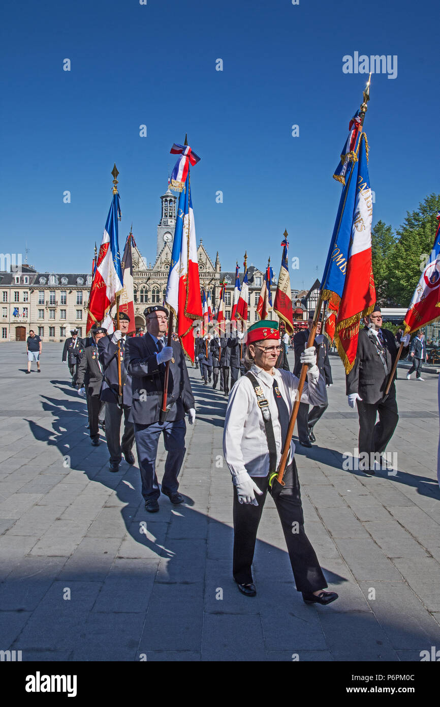 Männer marschieren mit erhobenen Bannern und Flaggen für Sieg in Europa VE Tag 8.Mai 2018 in Place de l'Hotel de Ville St Quentin, Aisne, Frankreich. Stockfoto