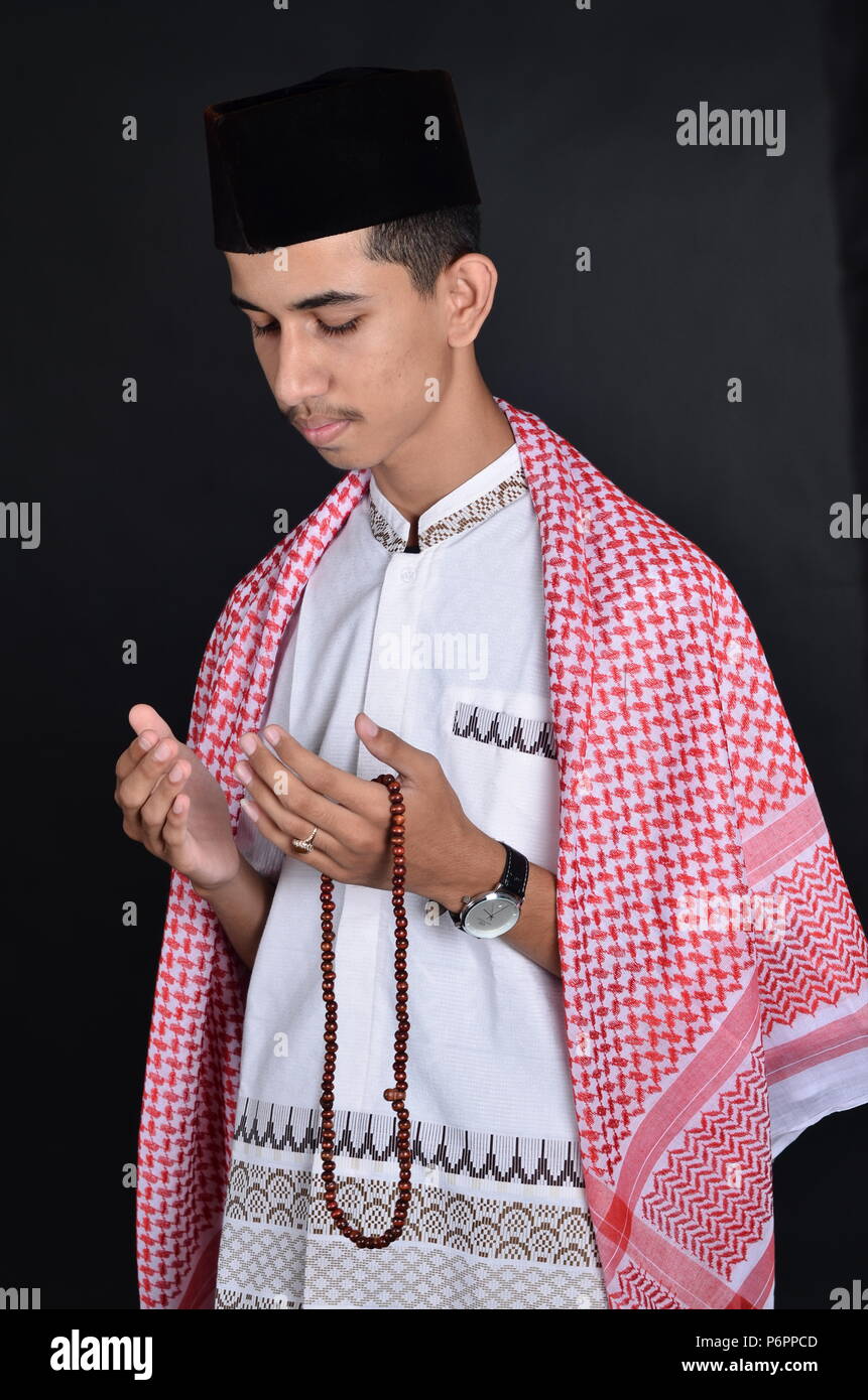 Jungen asiatischen muslimischen Mann, der betet mit gebetsperlen Stockfoto