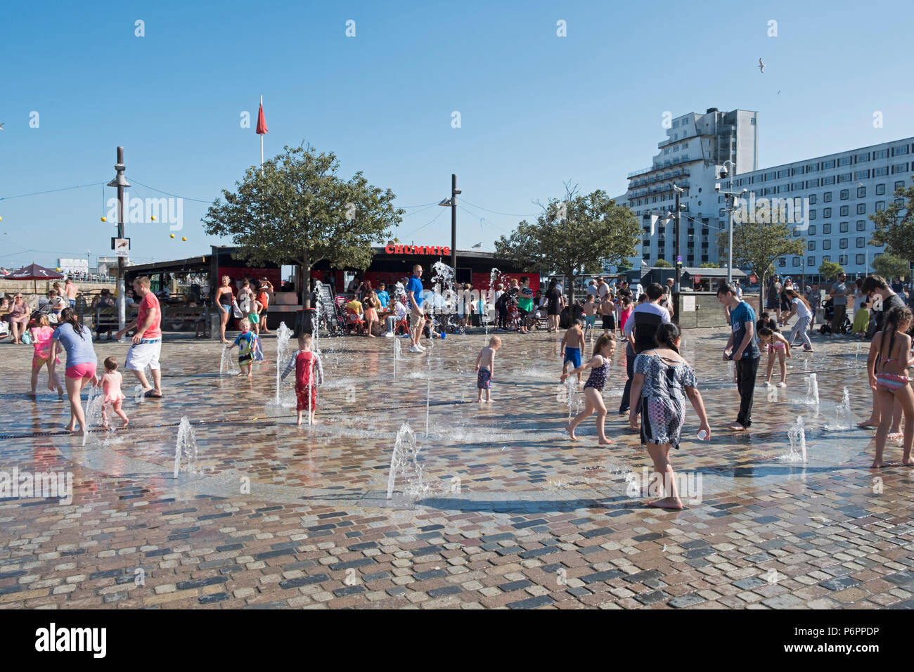 Kinder spielen in den Wasserfontänen am Fountain Square, Folkestone Harbour, Kent, Großbritannien Stockfoto