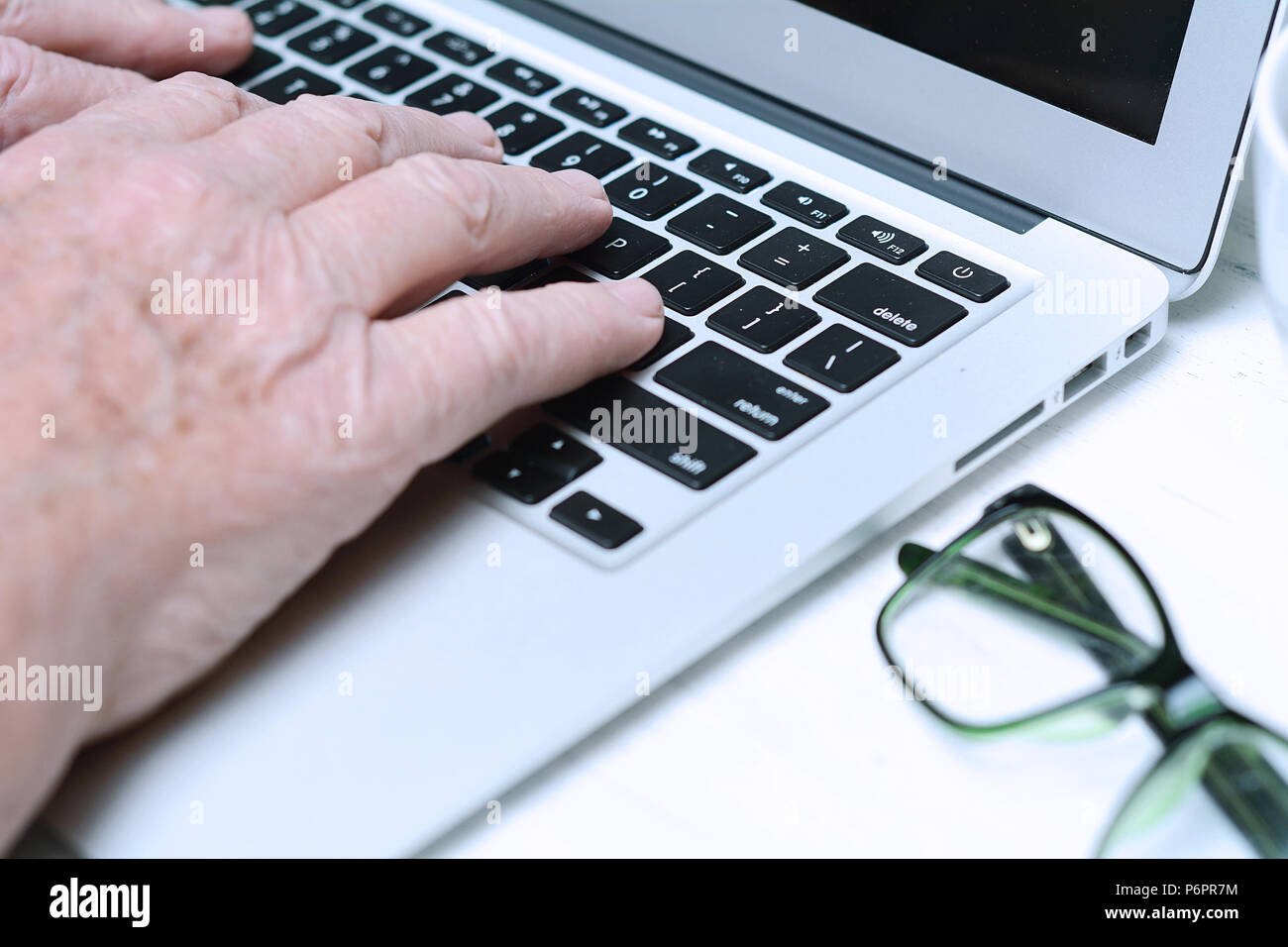 Nahaufnahme der Senior die Hände auf der Tastatur mit Tasse Kaffee und Gläser. Konzept Stockfoto