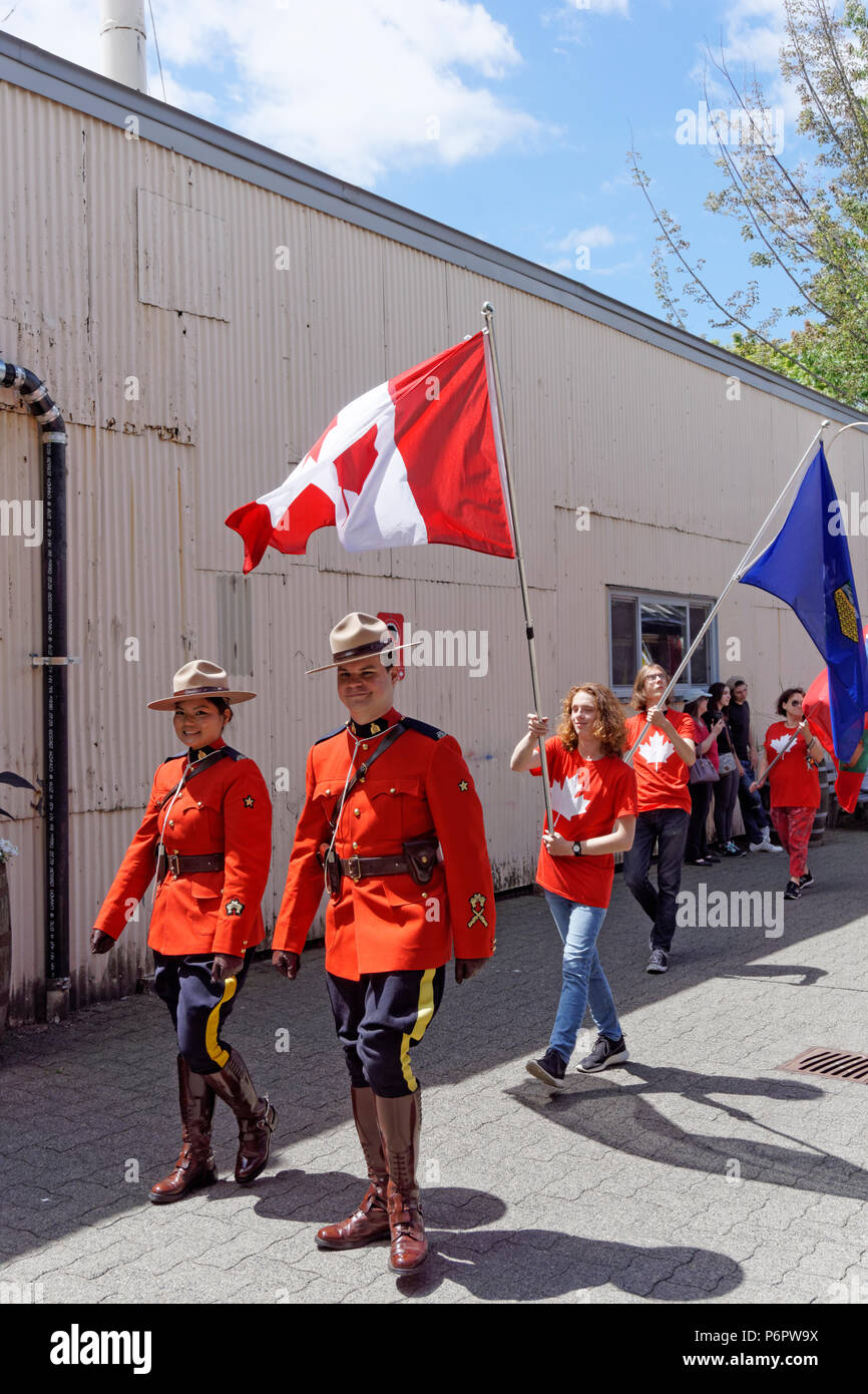RCMP Offiziere und Fahnenschwinger März in den jährlichen Canada Day Parade auf Granville Island, Vancouver, British Columbia. Stockfoto RCMP Offiziere und Fahnenschwinger März in den jährlichen Canada Day Parade auf Granville Island, Vancouver, British Columbia. Stockfoto