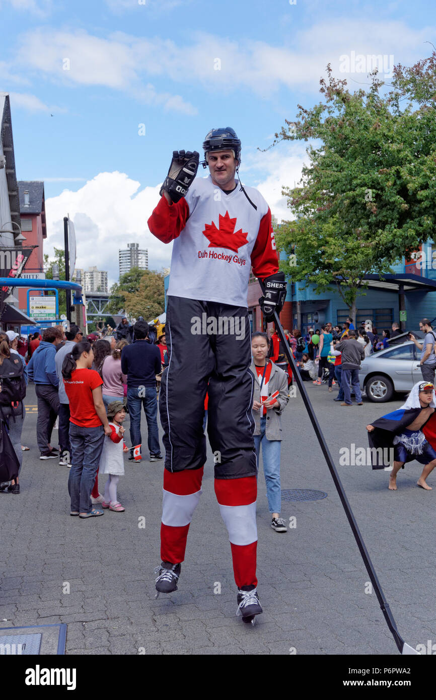 Ein Mann gekleidet wie ein kanadischer Eishockeyspieler auf Stelzen Wellen an Zuschauer in den jährlichen Canada Day Parade auf Granville Island, Vancouver, British Columbia. Stockfoto