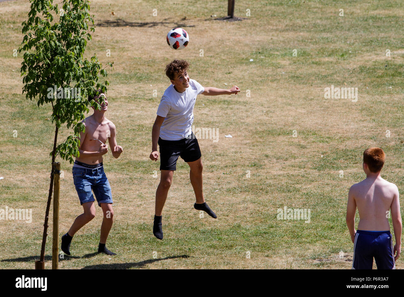 Badewanne, Großbritannien, 2. Juli 2018. Da das Vereinigte Königreich genießt einen sehr warmen und sonnigen Tag, eine Gruppe junger Männer abgebildet sind, da sie einen Fußball um in Parade gardens Kick, Meteorologen sagen voraus, dass das warme Wetter weiterhin gut in der nächsten Woche. Stockfoto