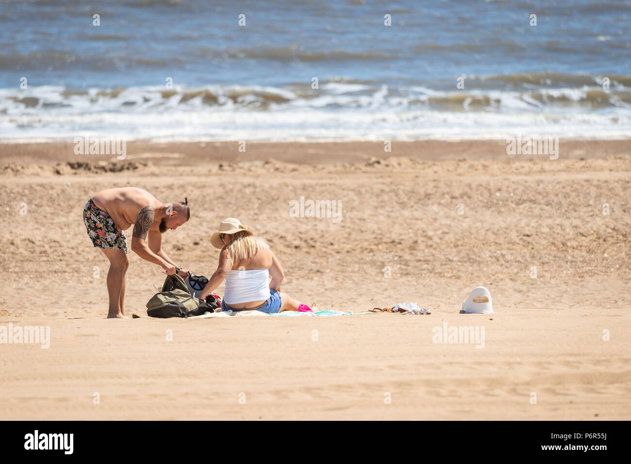 Skegness, Großbritannien, 2. Juli 2018. Ein junges Paar am Strand zu sitzen und die aktuelle heiße Wetter während einer Hitzewelle, die Temperaturen weiter zu 30 Grad in ganz Großbritannien zu erheben. Credit: Steven Booth/Alamy Leben Nachrichten. Stockfoto