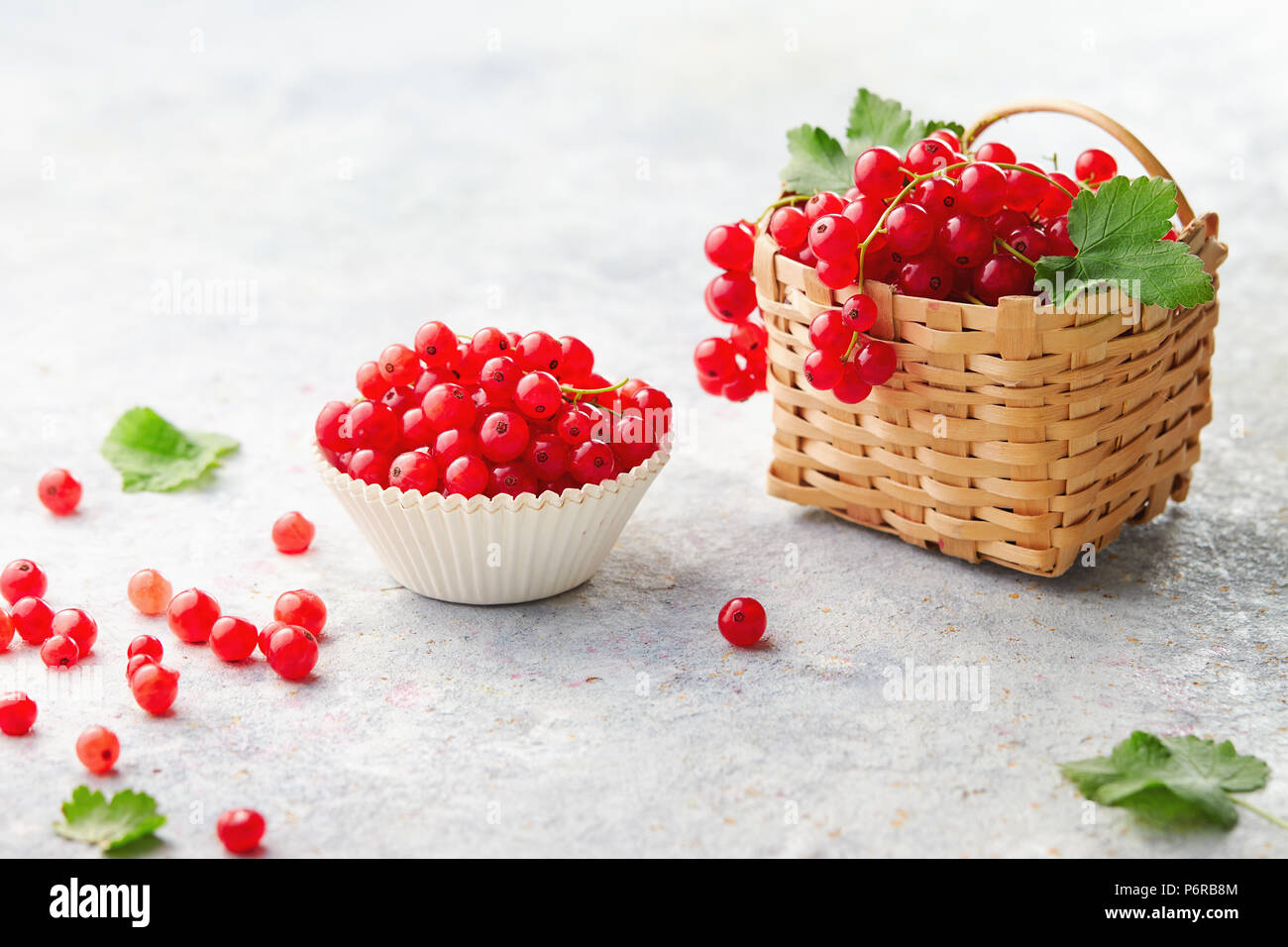 Backen Cup und ein wenig Weidenkorb mit Frische rote Johannisbeeren (Ribes rubrum). Stockfoto