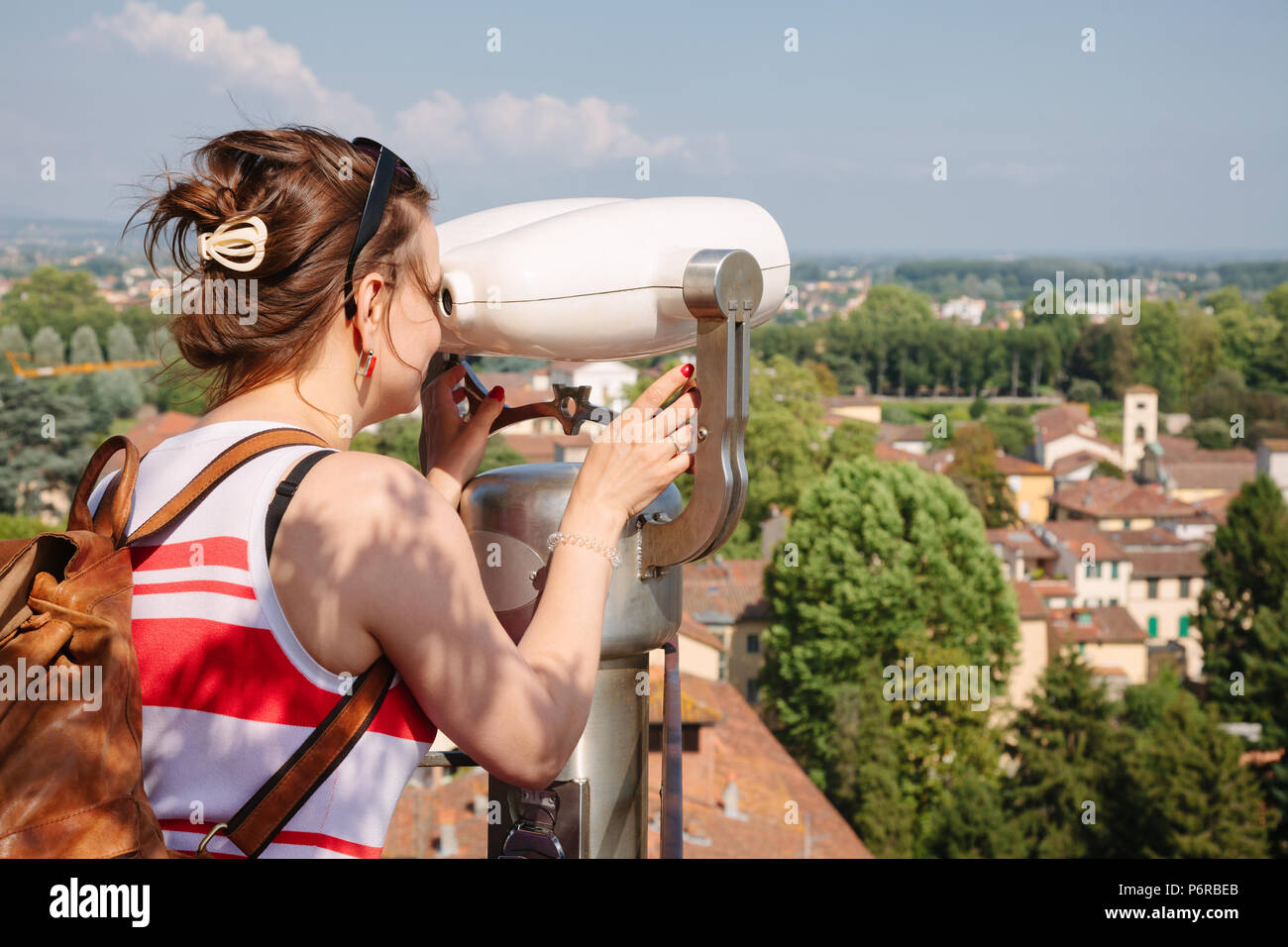 Junge Frau durch touristische binocular Teleskop beobachten Lucca Altstadt Stadtbild, Toskana, Italien Stockfoto
