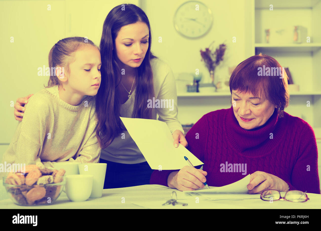 Schwere erwachsene Tochter mit Enkeltochter controlling Unterzeichnung der Dokumente durch die