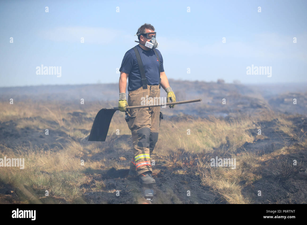 Ein Feuerwehrmann von Tyne und Wear Feuer- und Rettungsdienst setzt heraus das Feuer im Winter Hill in der Nähe von Bolton, als mehr als 20 Löschfahrzeuge sind an der Szene mit Besatzung die Bewältigung der Moorlandschaft Brände. Stockfoto