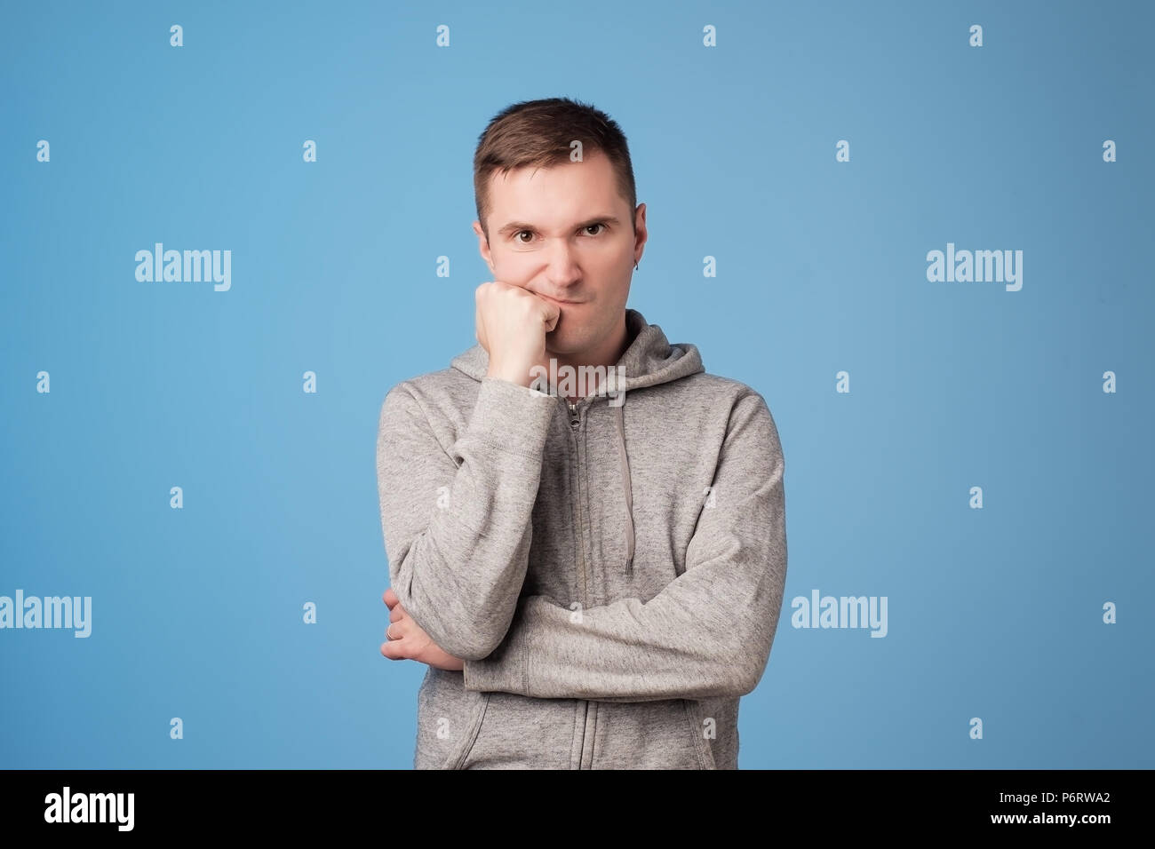 Studio shot der verärgerten Mann hält die Arme in der Nähe von Gesicht, skeptisch und unzufrieden aus ständigen Stockfoto