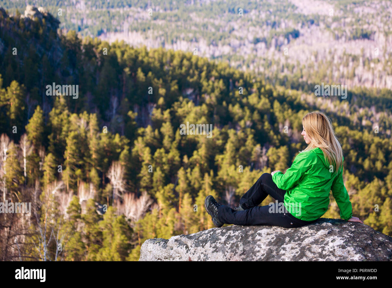 Junge Frau sitzt auf der Klippe. Stockfoto