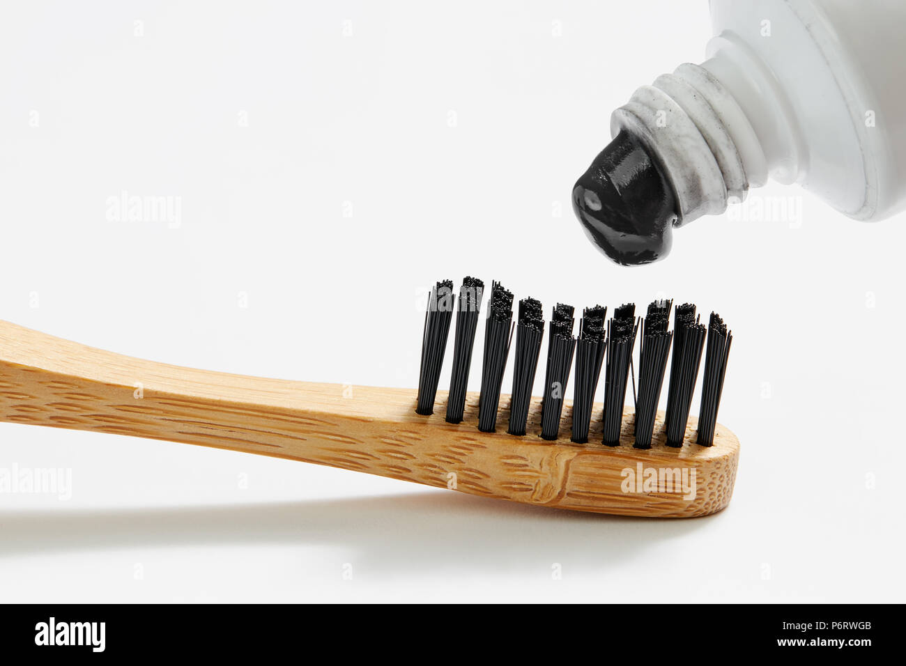 Zahnbürste mit Black Charcoal Zahnpasta. Nahaufnahme von schwarze Zahnpasta auf die Zahnbürste zusammendrücken. Stockfoto