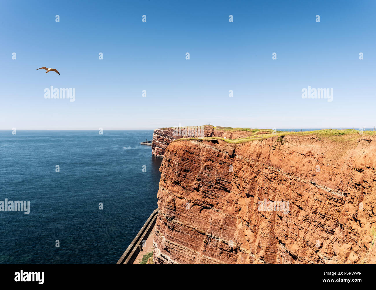 In rotem Sandstein, die Hohen Küste auf der Insel Helgoland gegen den blauen Himmel und Meer Stockfoto