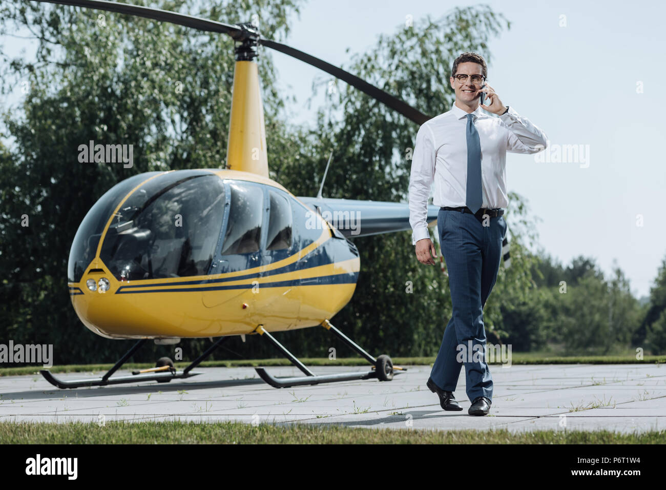 Fröhlicher junger CEO anrufen Taxi vom Hubschrauberlandeplatz Stockfoto