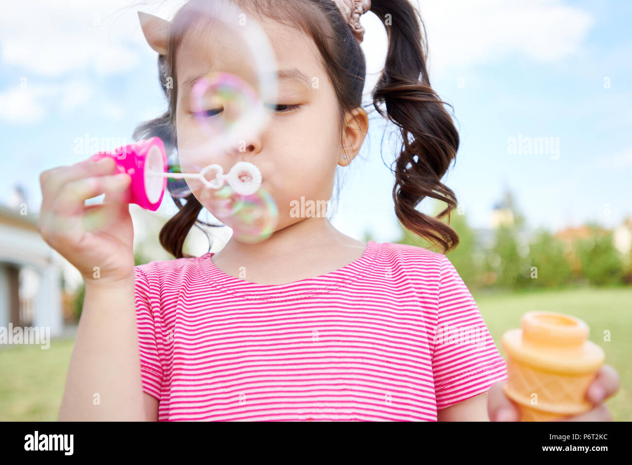 Süße asiatische Mädchen bläst Seifenblasen im Freien Stockfoto