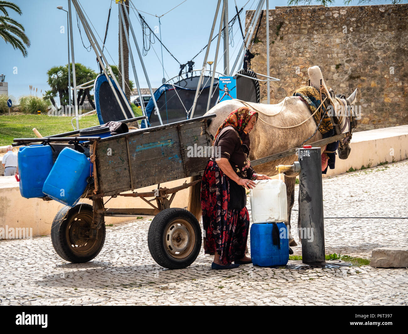Lagos, Portugal - May 18, 2018: Alte Frau kam Trinkwasser zu zeichnen. Lagos, Algarve, Portugal Stockfoto