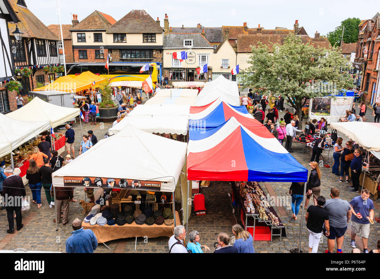 Hohen winkel Aussichtspunkt, der französische Markt von Le Wochenende Veranstaltung in Sandwich mittelalterliche Stadt, England. Vier Reihen von Ständen in der Stadt, Leute. Französische Fahnen Stockfoto