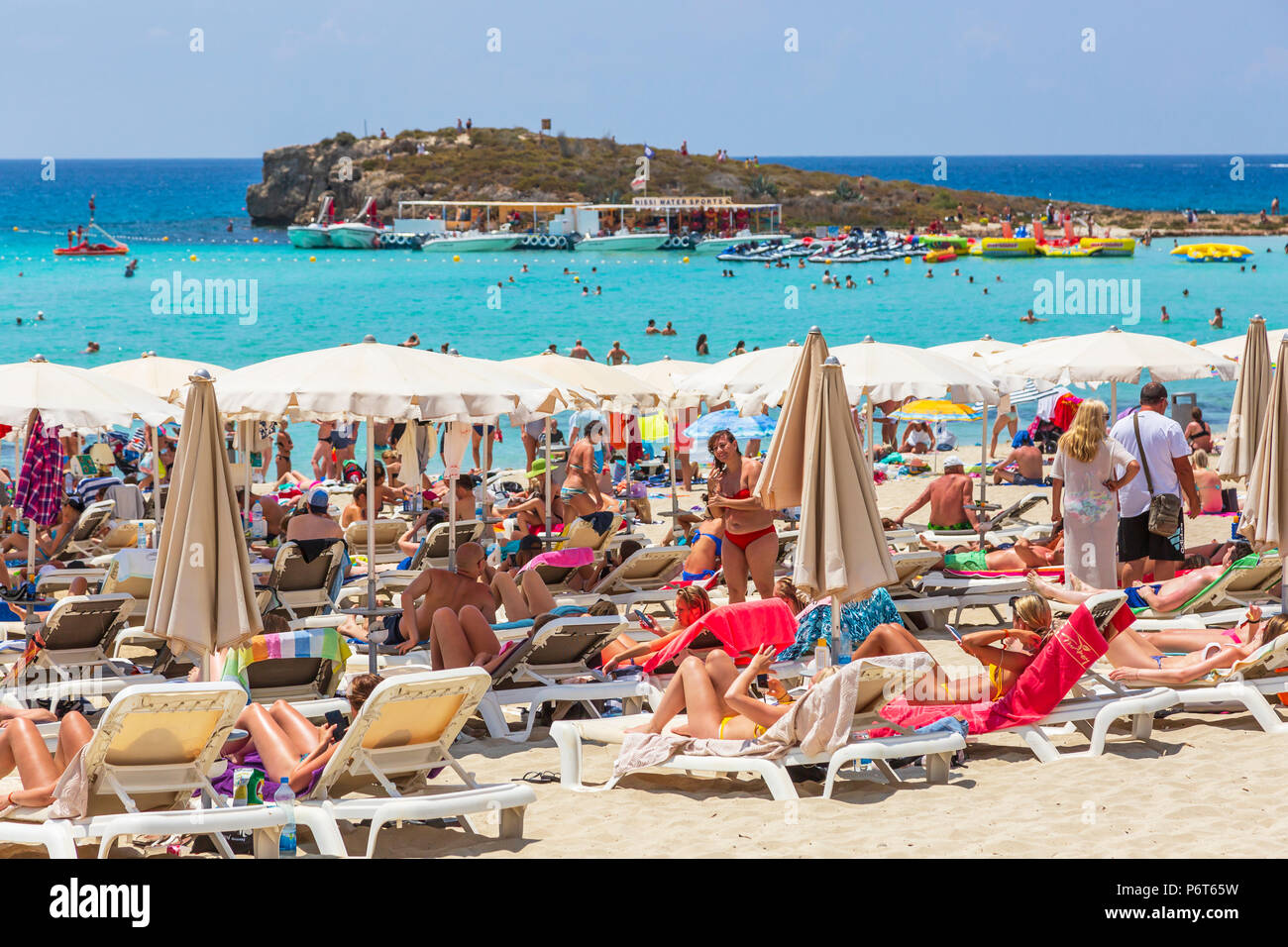 Touristen Sonnenbaden am Strand von Nissi Bay in der Nähe von Ayia Napa, Zypern Stockfoto